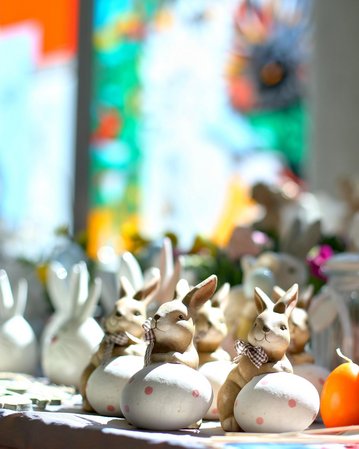 Dekorative Osterhasen und bunte Eier auf einem Tisch, umgeben von weiteren Frühlingsdekorationen.