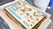Torte zum 60-jährigen Jubiläum der Kinderklinik Suhl, dekoriert mit bunten Blumen und einer Illustration eines Kindes mit einer Ärztin.