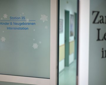 Tür zu Station 35, Kinder- und Neugeborenen-Intensivstation, mit dekorativen Schneeflocken auf der Glasoberfläche.
