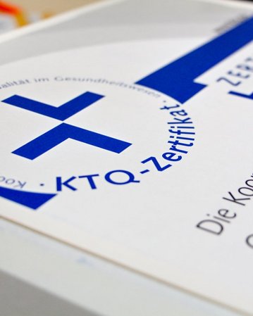 Ein Zertifikat mit dem Titel "KTQ-Zertifikat" und dem Untertitel "Die Kooperation für Transparenz und Qualität im Gesundheitswesen". Es zeigt ein Kreuzsymbol und ist auf einem weißen Hintergrund gedruckt.