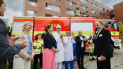 Eine Gruppe von Personen, darunter Feuerwehrleute und medizinisches Personal, steht vor einem Einsatzfahrzeug des Katastrophenschutzes Thüringen.